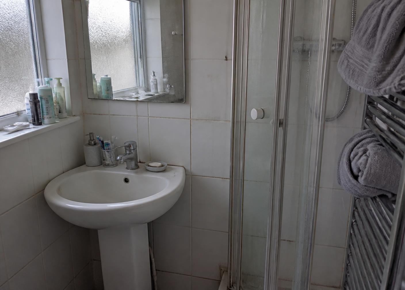 Bathroom with limescale on the tap, soap scum on the tiles and discoloured grout