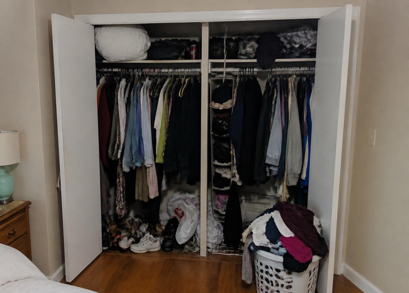 Overstuffed wardrobe with tangled hangers and shoes heaped on the floor