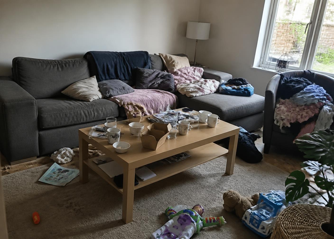 Untidy living room with scattered toys, blankets and mugs on the coffee table